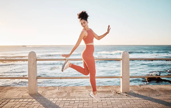 Fitness, happy running and woman jumping on beach path on fun morning exercise with freedom and happiness. Run, jump and smile, excited girl on healthy ocean walk with joy, wellness and workout goals.