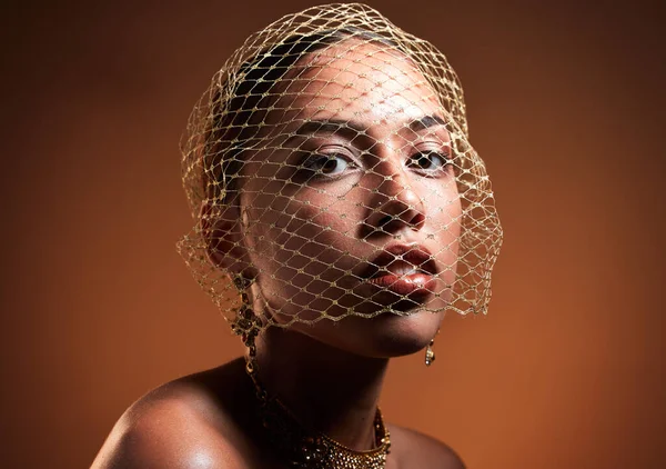 Stylish, elegant and portrait of a model with a net veil isolated on a brown background in studio. Fashion, vintage and face of a young retro model with a fashionable facial accessory on a backdrop.
