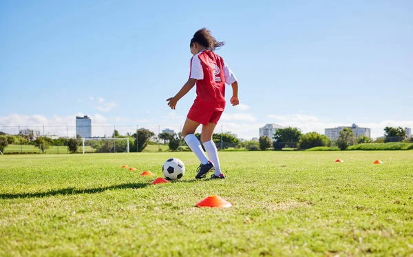 Football girl child, field and training for fitness, sports and development of balance for control, speed and strong body. Female kid, fast soccer ball dribbling or workout feet on grass for learning.
