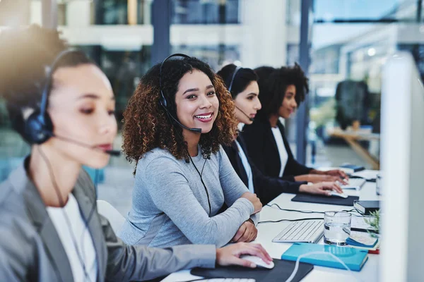 I get to help people every day. Cropped portrait of an attractive young businesswoman sitting in the office with her coworkers and wearing a headset