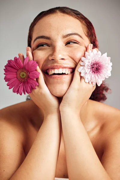 stock image Woman, flowers and studio headshot with smile for beauty, wellness or skincare with spring aesthetic by backdrop. Model, girl and carnation plant for cosmetic health, skin glow and happy for growth.