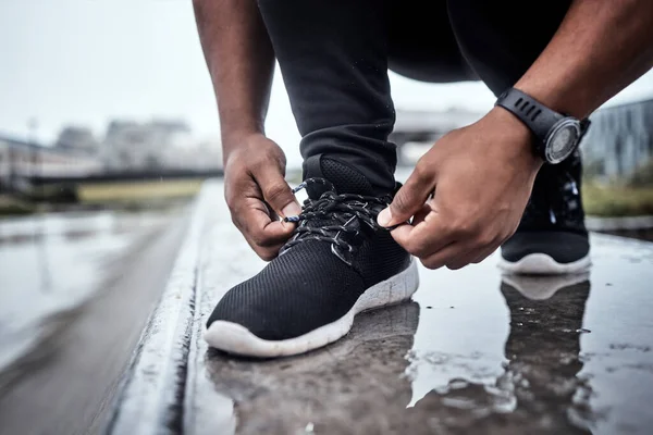 Fitness, shoes and running with a sports man tying his laces for an outdoor cardio or endurance workout. Exercise, footwear and training with a male athlete or runner fastening his shoelaces outside.