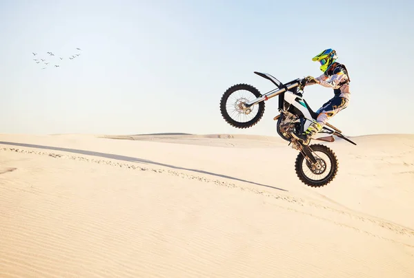 Motorcycle, desert race and air jump for extreme sport expert with agile speed, power or balance in nature. Motorbike man, rally and blue sky on fast vehicle with helmet, safety clothes or motivation.