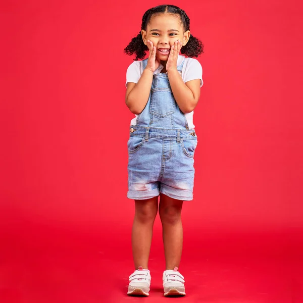 Happy, youth and portrait of girl on red background for happy childhood, positive mindset and smile. Fashion, summer style and cute face of girl in studio with funny, comic and meme facial expression.
