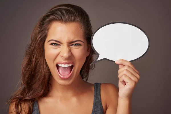 Its enough to make me want to scream. Studio shot of an attractive young woman holding a blank speech bubble and shouting against a gray background