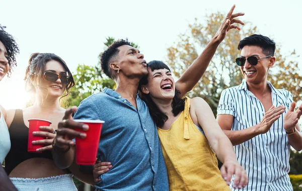 Drinks, party and a couple of friends dancing outdoor to celebrate at festival, concert or social event. Diversity young men and women people together in summer, happy and drinking alcohol in crowd.