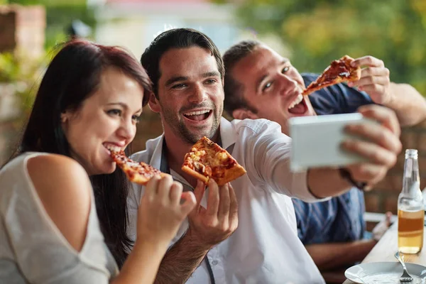 Pizza time is selfie time. a group of happy young friends posing for a selfie together at a backyard dinner party
