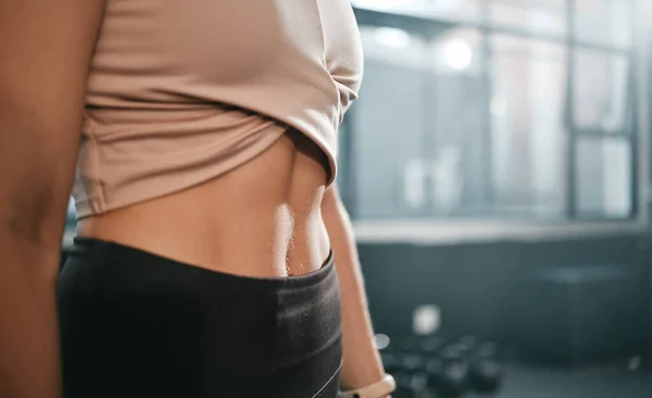 Fitness, stomach and woman in a gym for exercise, health or wellness for weightloss training. Sports, tummy tuck and closeup of a slim female athlete or model abs after a workout in a sport center