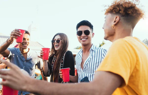 Group of friends, drinks and a party outdoor to celebrate at festival, celebration or summer social event. Diversity young men and women people together while talking, happy and drinking alcohol.