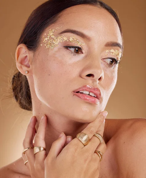 Face cosmetics, facial glitter and woman with luxury gold eyeshadow, beauty product and skincare glow. Makeup, spa salon or aesthetic model girl with jewelry ring, accessories and healthcare wellness.