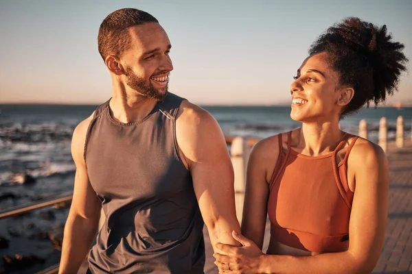 Black couple, fitness and walking at the beach with smile for conversation, talk or sunset together in the outdoors. Happy man and woman enjoying fun walk smiling for holiday break by the ocean coast.