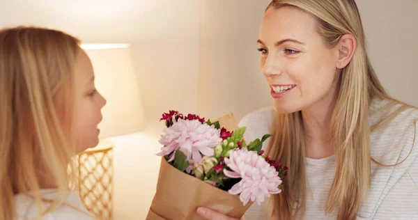 Flowers, gift and happy with mother and girl for mothers day, birthday or congratulations in family home. Gratitude, smile and love with child giving bouquet to mom for present and celebration.