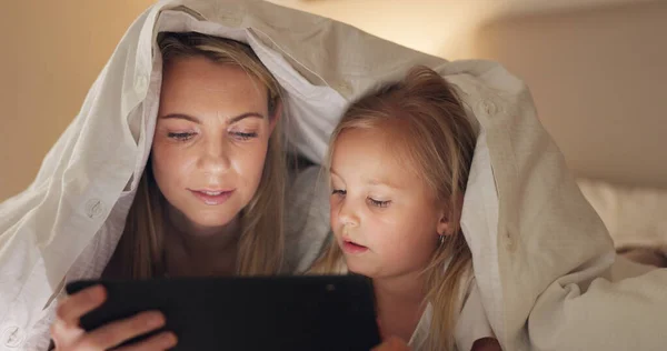Tablet, mother and girl with bedroom blanket fort at night in house on education website, learning or study game. Woman, child and digital technology in family home for internet ebook bedtime bonding.