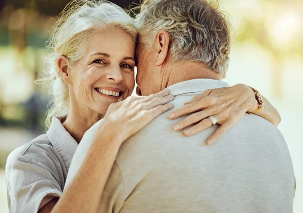 Hug, affection and portrait of a senior couple in nature for bonding, quality time and care in France. Smile, happy and face of an elderly woman hugging a man for romance in retirement in a park.