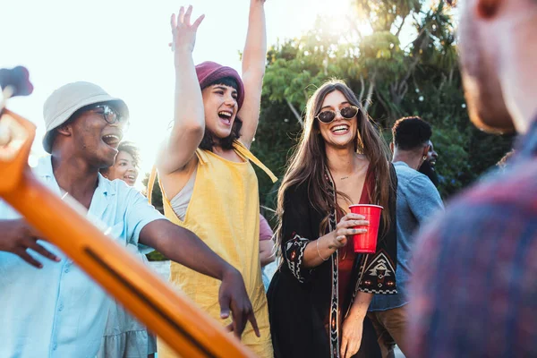 Music, drinks and friends dancing outdoor to celebrate at festival, concert or summer social event. Diversity young men and women people together while excited, happy and drinking alcohol at a party.