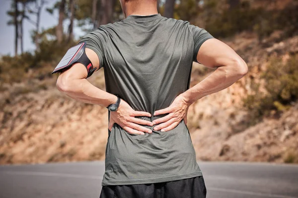 フィットネス 背中の痛みやスマートフォンのランニングトラッカーをサポートするための外傷性筋肉の手で道路の男 運動や屋外ワークアウト 損傷を持つランナー 脊椎の緊張や痛みを伴う筋肉 — ストック写真