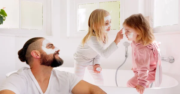 Father, girl kids and face mask in bathroom in for comic bonding, smile and happy together for skincare. Happy, dad and daughter children with cream, facial and beauty for skin with funny happiness.