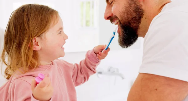 Happy family, dental and brushing teeth with girl and father in bathroom for hygiene, learning and grooming. Love, teeth and oral care by parent with daughter play, laugh and cleaning in their home.