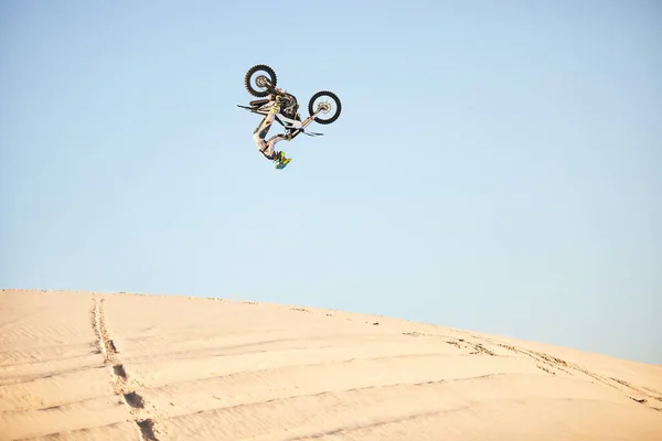 Motorcycle, jump and sports athlete in desert, dirt bike rally outdoor with extreme sport stunt, power and action. Nature, adventure and freedom, fitness challenge and biker person, mockup and travel.