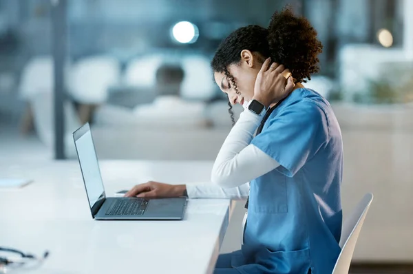 Doctor, laptop and neck pain at night overworked, stressed or burnout by desk at the hospital. Woman medical professional suffering from painful injury, ache or inflammation working late on computer.