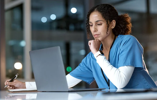 Doctor, thinking and writing with laptop at night for healthcare solution, idea or planning at hospital. Woman medical nurse working late in focus for research with notebook and computer at clinic.