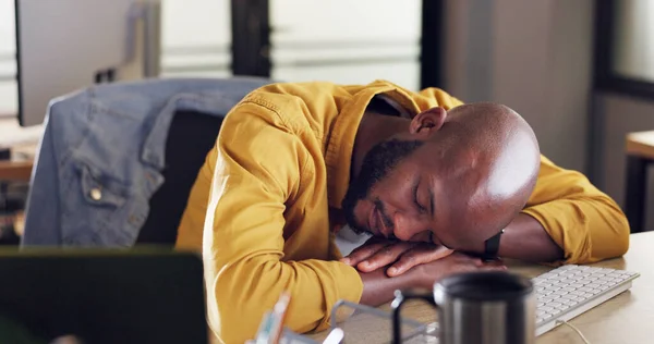 Black man, sleep and office desk with tired and fatigue from burnout and working late at small business while exhausted and needing rest. Lazy male at startup company feeling sick and taking nap.