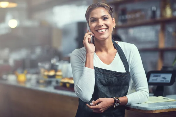 Connecting with customers has never been easier. a young woman using a phone in the store that she works at