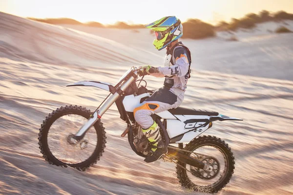 Motorcycle, athlete and sports outdoor with speed, fitness and riding in desert with extreme sport, fast and safety helmet. Challenge, power and biking exercise, person training and dirt bike rally.