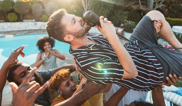 Microphone, singing and crowd surfing with a man performer at a party outdoor during summer. Concert, energy and audience with a male singer being carried by a group of people at a performance event.