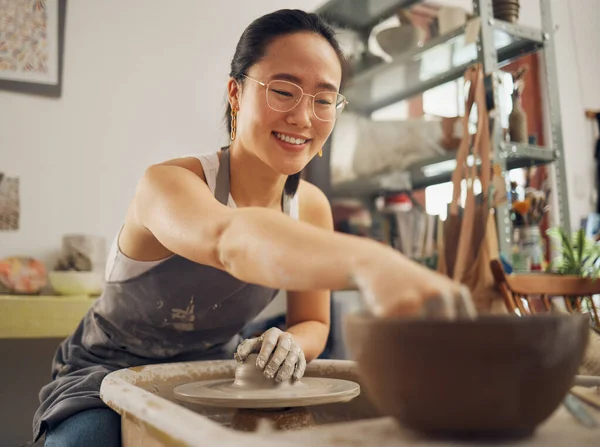 Happy, pottery or woman in designer workshop working on cup sculpture or mug mold in small business. Smile, artistic girl or creative Japanese worker busy with handicraft products as entrepreneur.