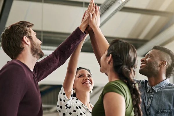 Strong team players make for a strong team. a team of colleagues giving each other a high five in a modern office