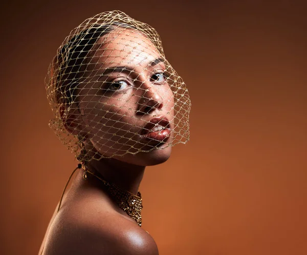 Vintage, fashionable and portrait of a woman with a net veil isolated on a brown background in studio. Fashion, stylish and face of a young retro model with a classy facial accessory on a backdrop.