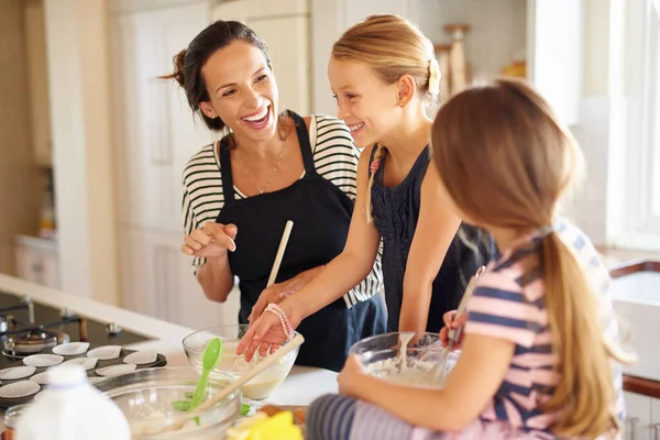 Youre doing a great job. two little girls baking with their mother in the kitchen
