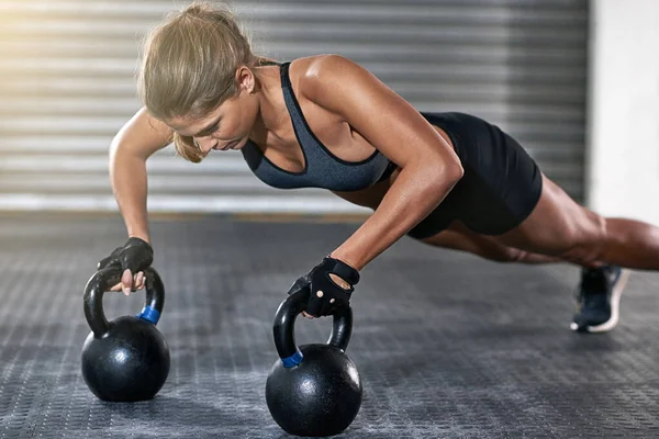 Shes a monster in the gym. a young woman working out with kettle bells at the gym