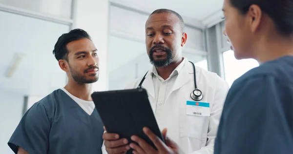 Tablet, doctor and nurses conversation, communication and online research in hospital. Black man, medical professional or staff talking, digital schedule for surgery or smile for results or diagnosis.