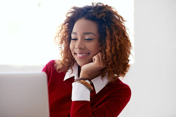 She enjoys the work she does. a young woman working on a laptop in an office