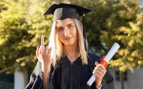 University student woman, middle finger and holding certificate in portrait, hand sign and success. Gen z girl, graduate celebration and education with smile, happiness or diploma for degree.
