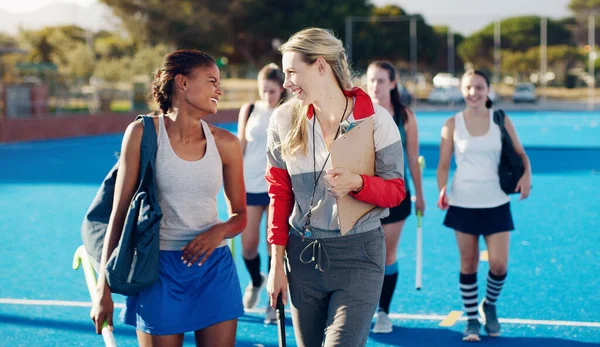 Team leader, hockey and happy discussion with player for coaching, teamwork or collaboration in the outdoors. Fitness sporting coach talking with athlete in friendly conversation for training tips.