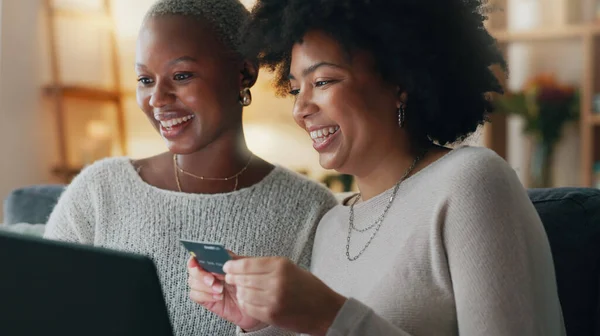 Payment, credit card and friends online shopping on a laptop for discount or sale on a digital fintech website at home. Ecommerce, happy and excited African women on the sofa banking on the internet.