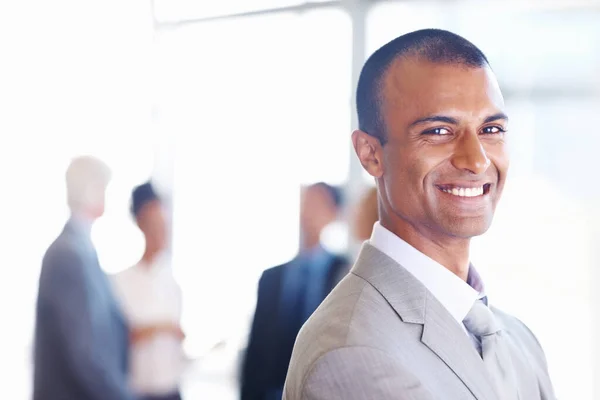 African American business man smiling with team. Closeup of African American business man smiling with associates in background