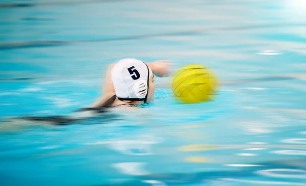 Sports, water polo and athlete swimming with a ball for a competition, exercise or hobby. Fitness, blur motion and swimmer training to play a professional sport game or match in a indoor pool