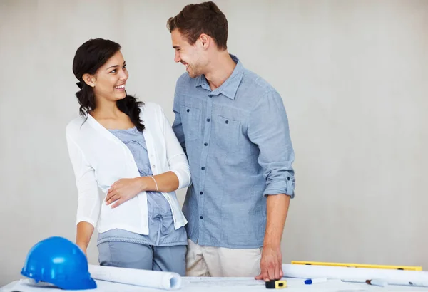 Cheerful young couple discussing house plan. Cheerful young couple smiling while discussing house plan