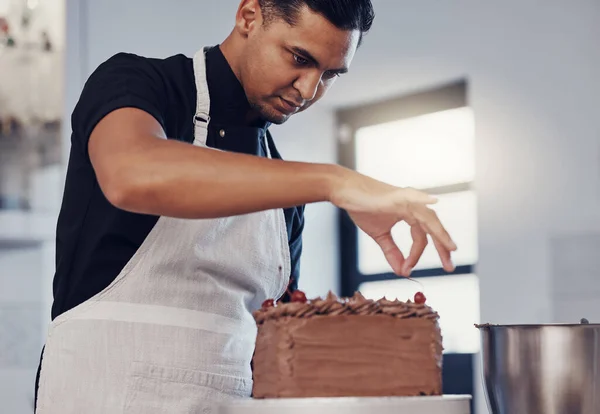 Kitchen, baking and man decorating cake with chocolate sprinkles and frosting with focus and skill. Sweets, small business and baker decorating dessert for birthday event and pastry chef in bakery