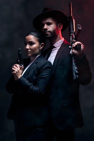 Gangster couple, fashion or gun on studio background in secret spy, isolated mafia safety or crime lord security. Man, love or model woman with pistol in stylish, trendy or fashion clothes aesthetic.