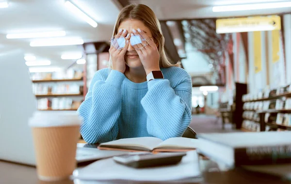 Woman student with glasses, stress with headache and burnout, tired about paper deadline or study for exam in library. Campus, college studying fatigue with scholarship problem, pain and eye strain.