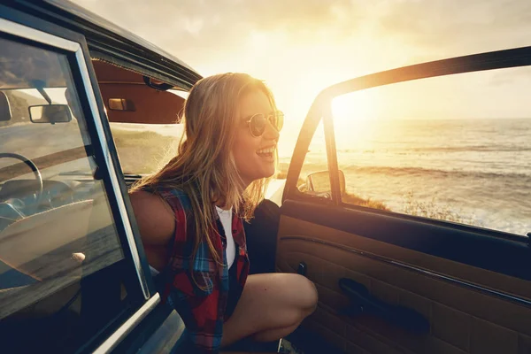 Woman, sunset and beach road trip by car door with smile, freedom and happiness for summer vacation. Happy gen z girl, suv and sunglasses for sunshine, outdoor adventure or holiday by waves on travel.