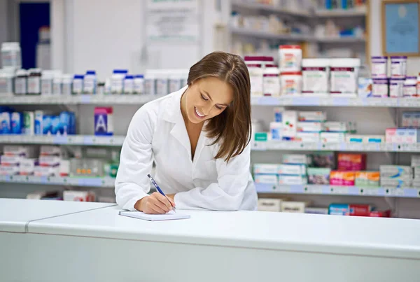 Keeping track of prescriptions. an attractive young pharmacist working at the prescription counter