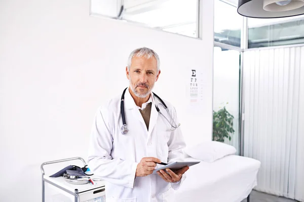 Ive got your medical history right here. Portrait of a mature male doctor standing with a digital tablet in a medical building