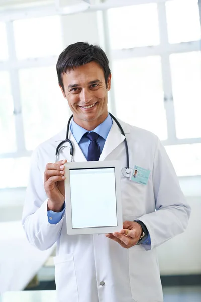 Let me show you how the procedure works. Portrait of a handsome young doctor holding up a tablet so that the screen is facing the camera