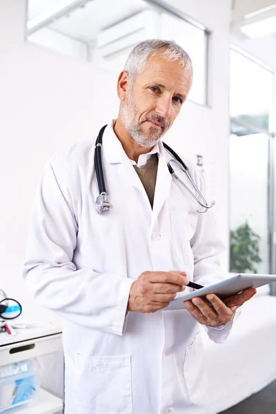 Its a great diagnostic tool. Portrait of a mature male doctor standing with a digital tablet in a medical building